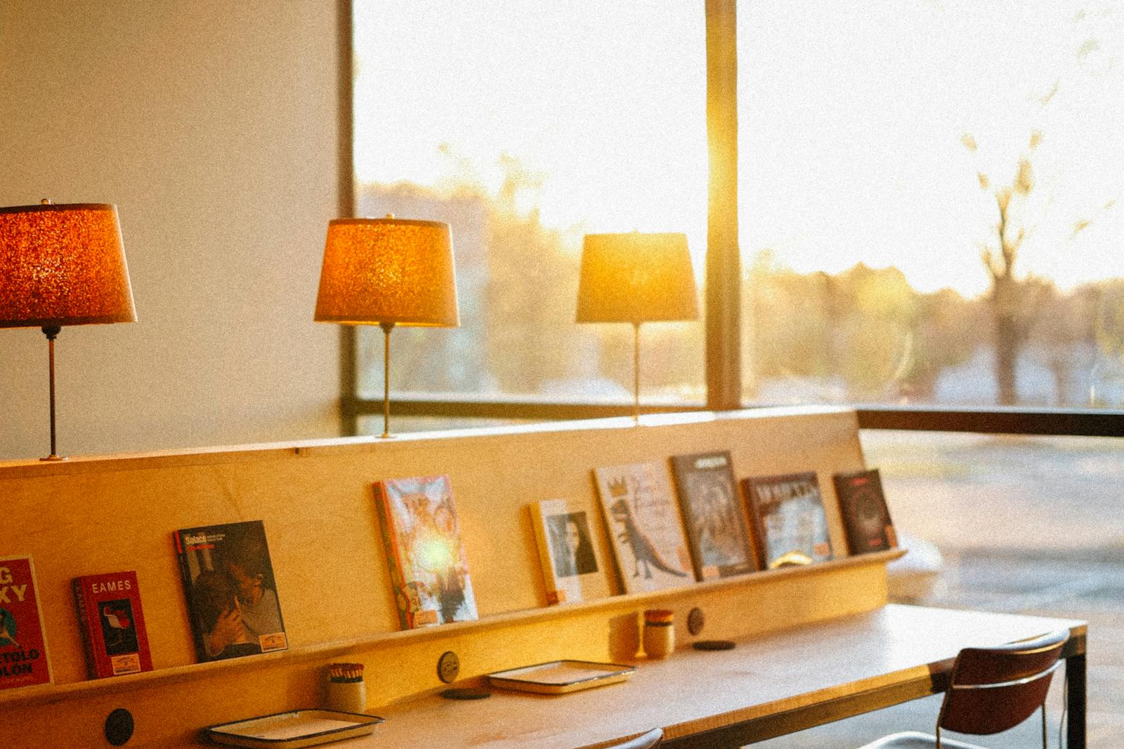Long wooden table lined with lit lamps and books at golden hour